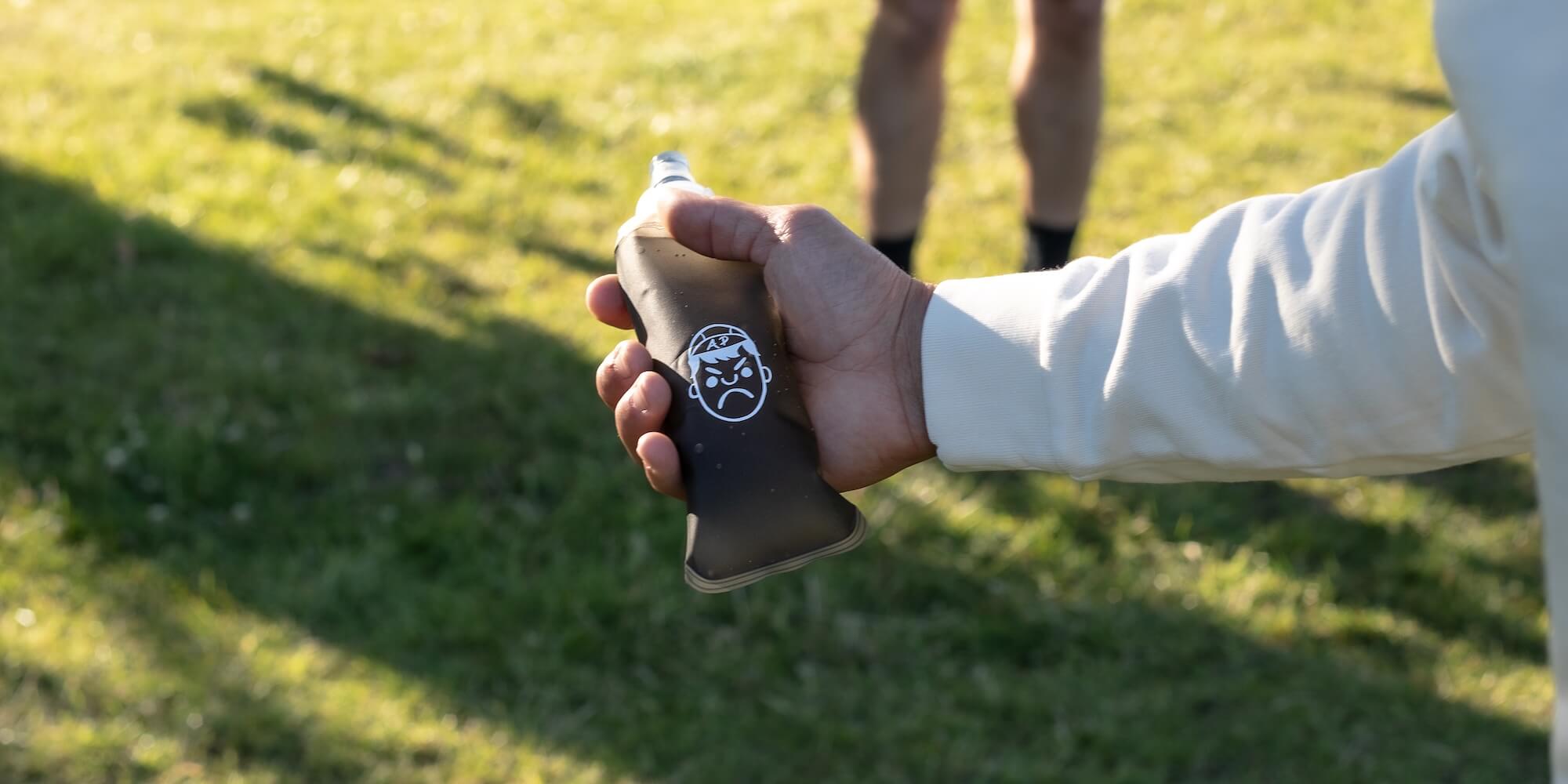 Someone holding an Angry Pablo soft flask for running in a field